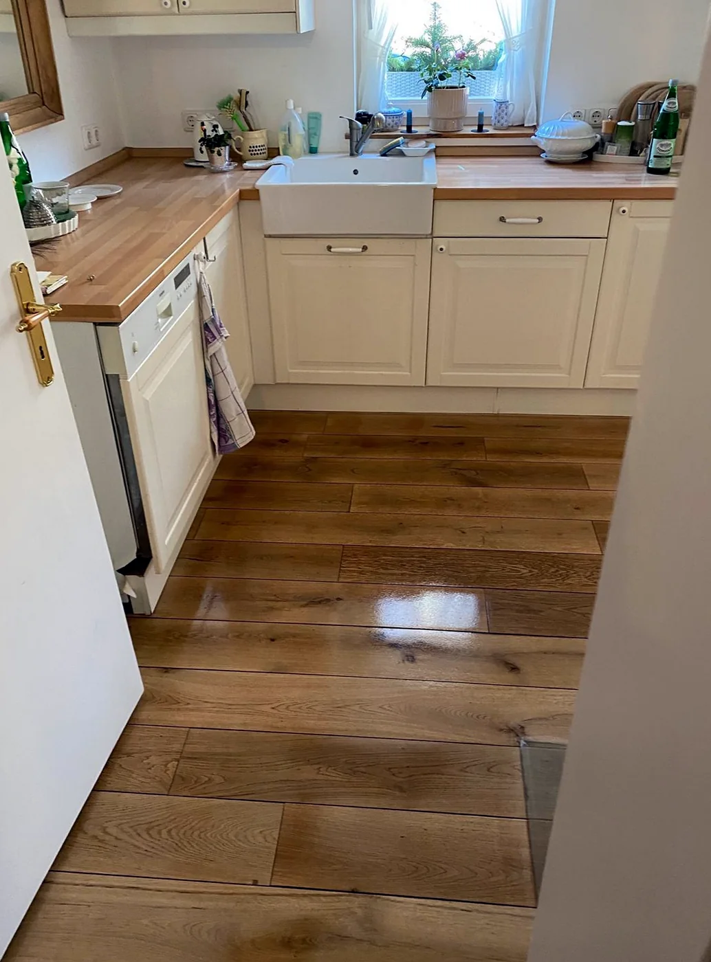 Blick in die Küche mit neu versiegeltem Eichenparkett, Landhausküche in Creme mit Holzarbeitsplatte und Belfast-Spüle