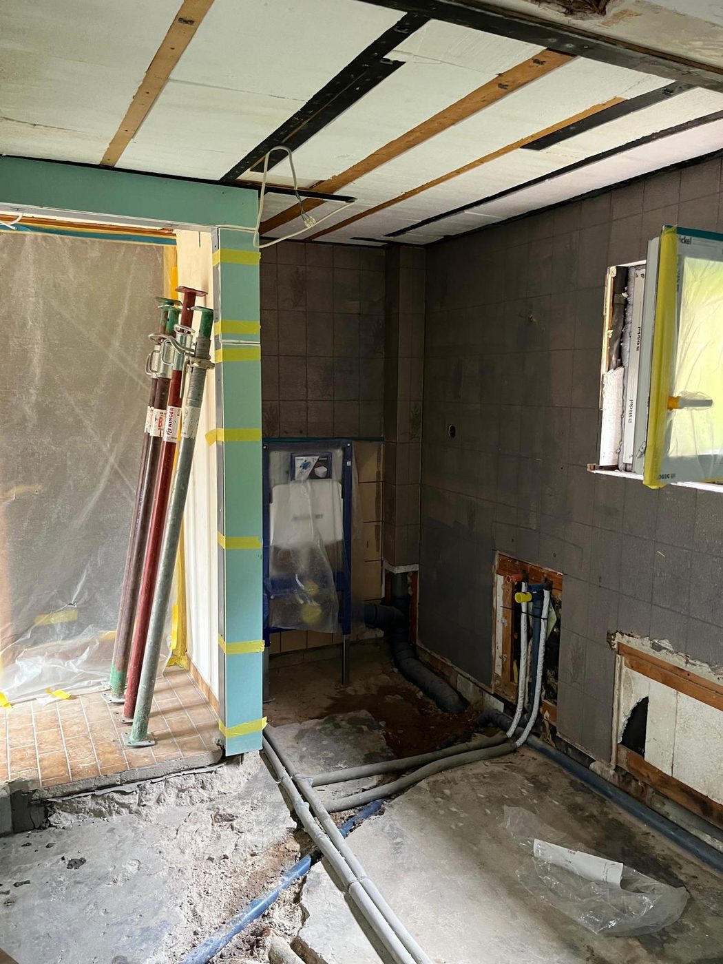 Rohbauphase mit Vorwandelement für das Wand-WC, verlegten Abwasser- und Frischwasserleitungen und abgeklebter Staubschutzwand