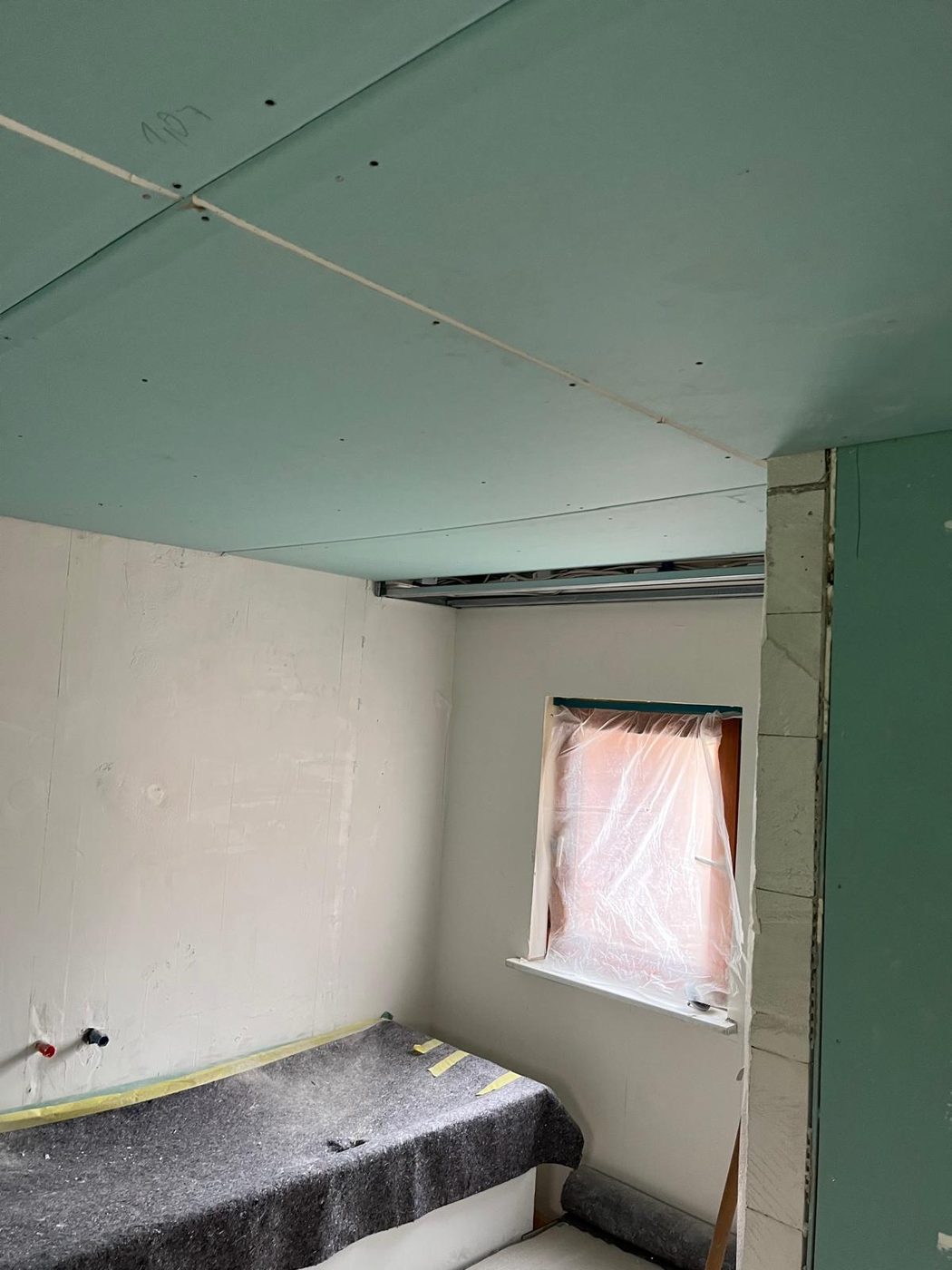 Neue abgehängte Decke aus Feuchtraum-Gipsplatten, Fenster abgeklebt, Wände vorbereitet