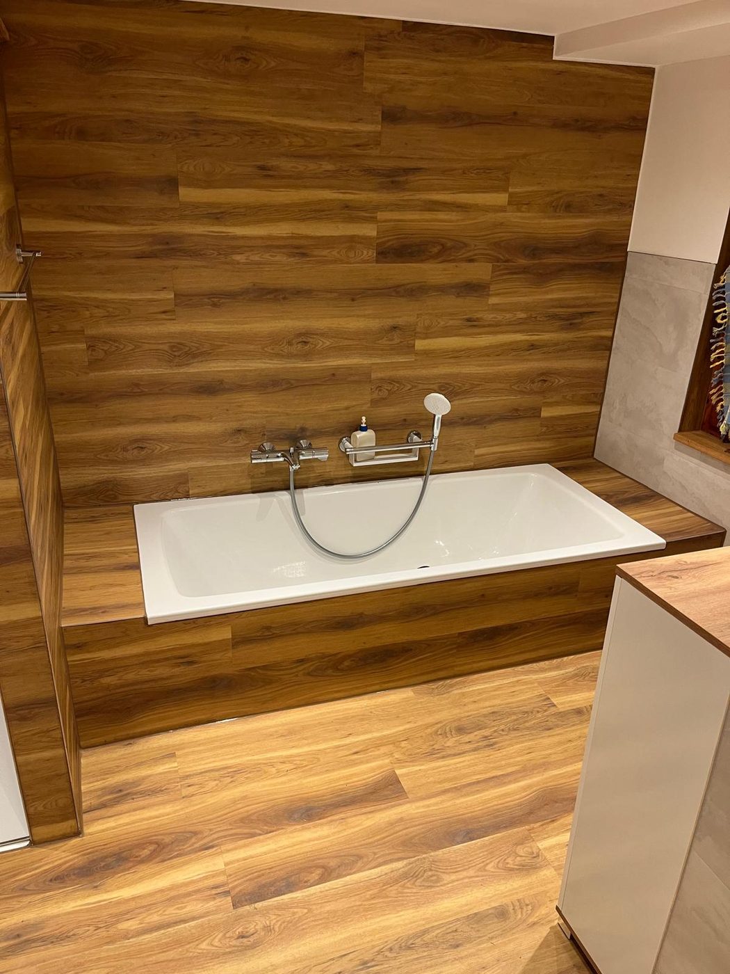 Fertige Badewanne mit Wandverkleidung aus Vinyl in warmer Holzoptik, Wannenrand und Boden im gleichen Belag