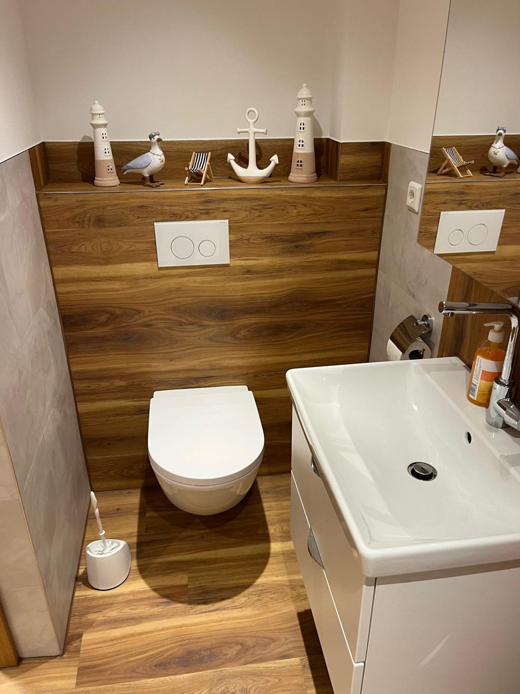 Wand-WC vor Vinyl-Holzoptik mit Ablagesims, daneben Waschtisch mit Unterschrank und großer Spiegel