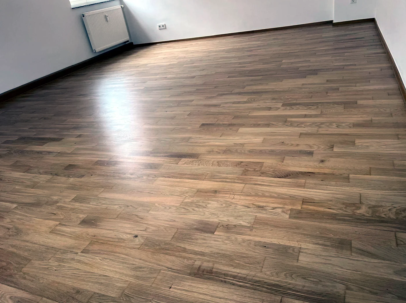 Großflächig verlegtes Eichenparkett, frisch versiegelt mit gleichmäßigem Seidenglanz