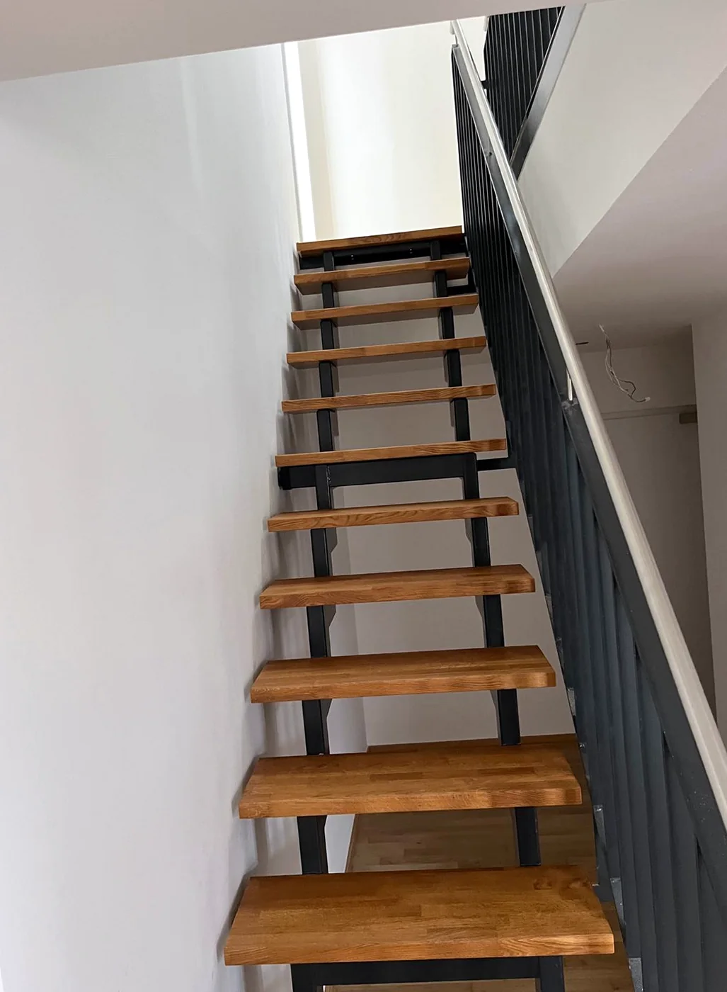 Freitragende Treppe mit massiven Eichenstufen auf schwarzer Stahlkonstruktion